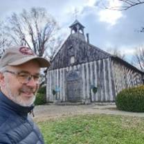 A person taking a selfie in front of a wooden church

AI-generated content may be incorrect.